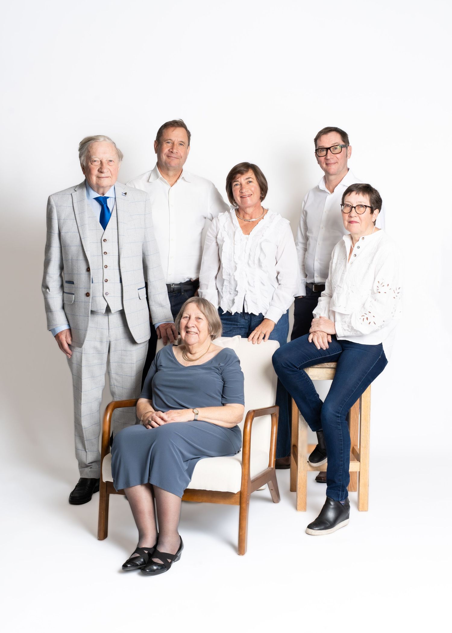 A series of four studio portraits showing elderly couples sitting together on wooden chairs against a white backdrop.