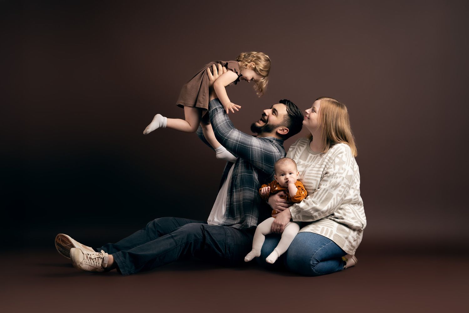 A series of intimate family portraits showing playful moments between parents and children against a dark background.