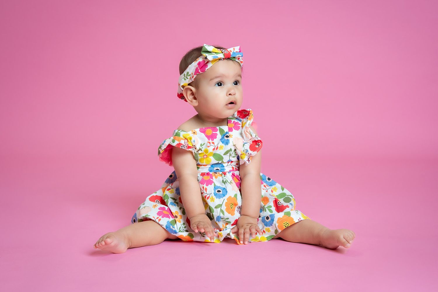 Young baby girl sitting in colourful outfit for a 1st birthday photoshoot near Shrewsbury
