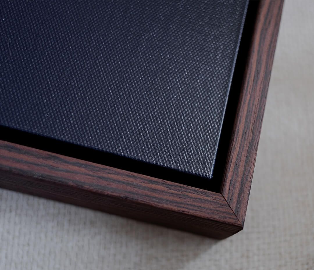 Dark blue textured fabric material in wooden frame showing corner detail and mounting hardware.