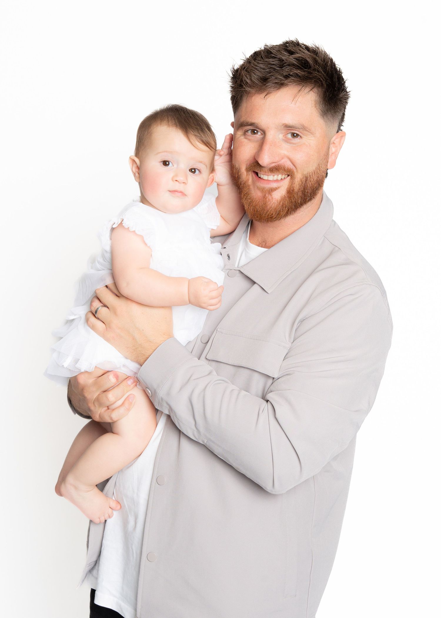 Man in light gray suit holds and poses with a baby in multiple similar shots showing different angles and expressions.