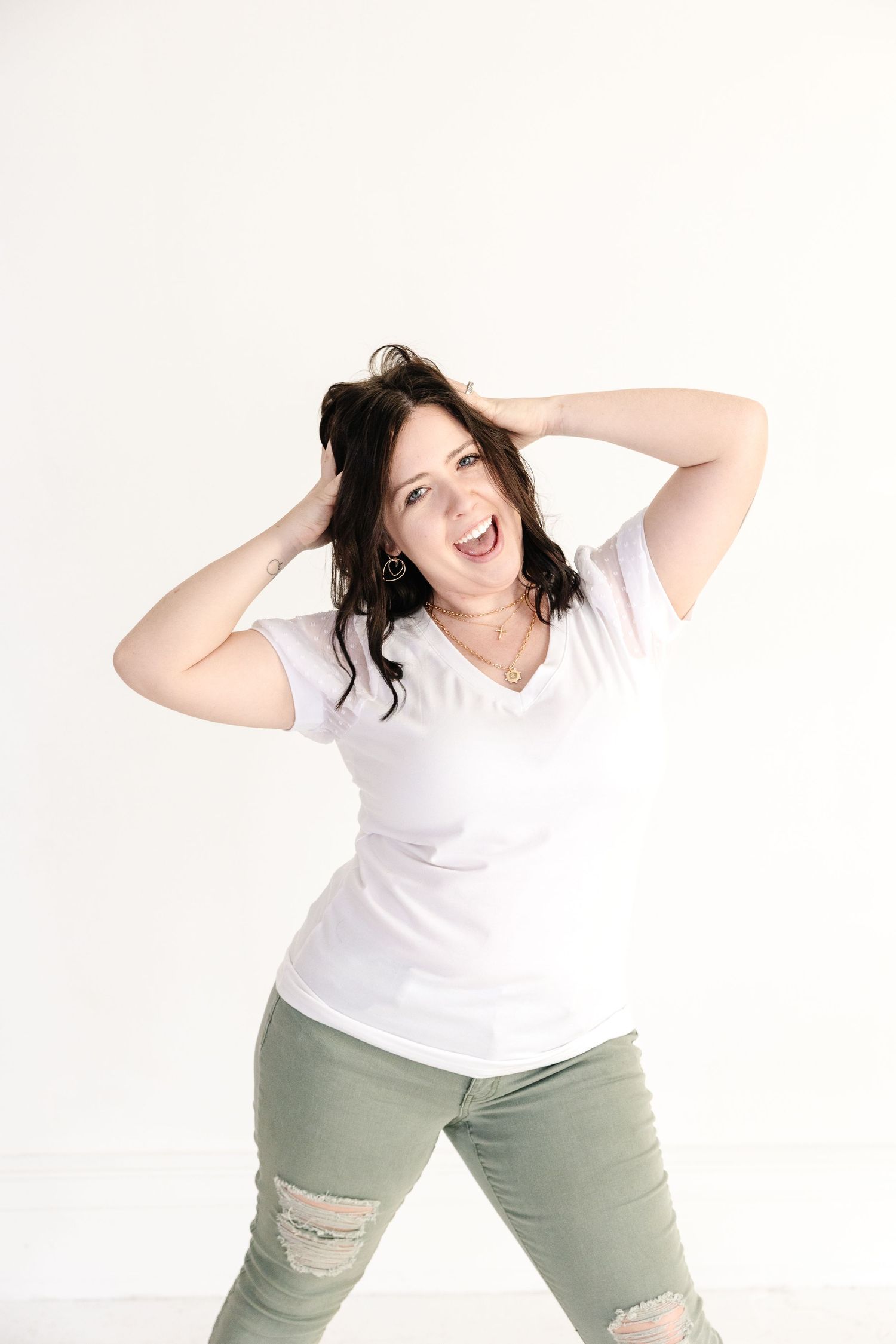 Pittsburg KS and Joplin MO Brand and Family Photographer in white t-shirt and green pants poses energetically during branding photoshoot.