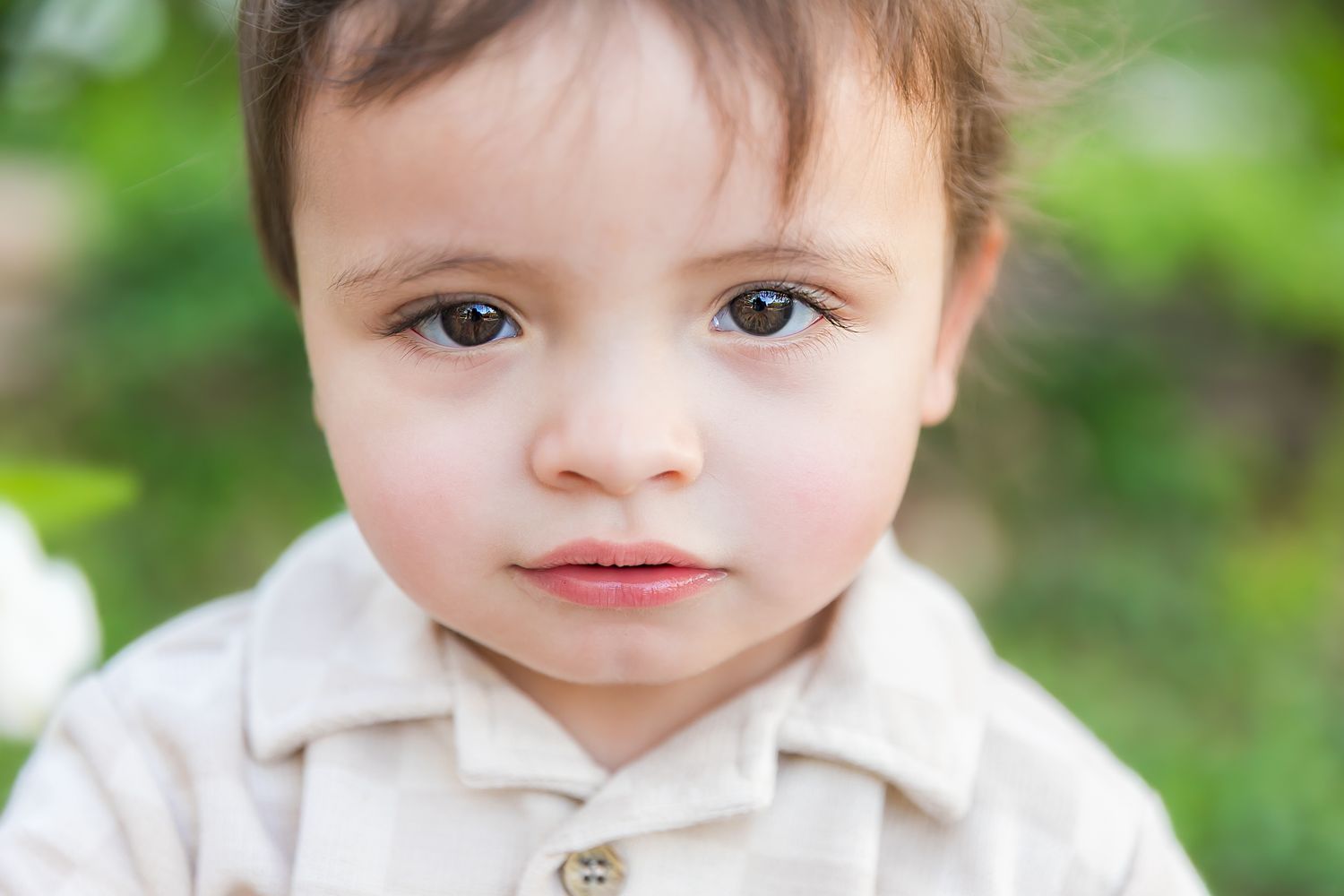 A close up of a child with dark hair and expressive eyes outdoors for milestone birthday photos at Pitt State University in Pittsburg KS.