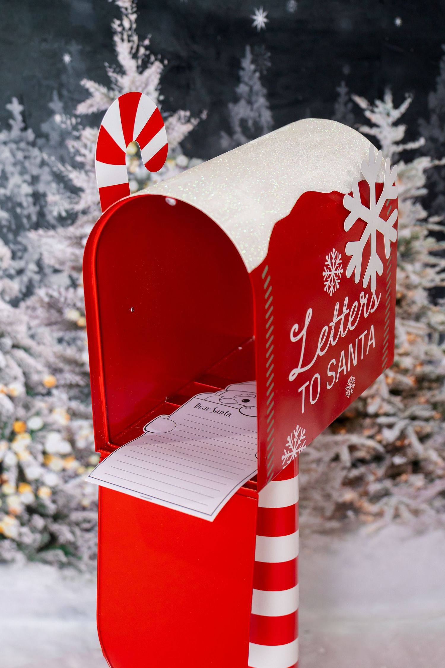 A festive red mailbox decorated with white snowflakes and labeled 'Letters to Santa' sits against a snowy winter backdrop.