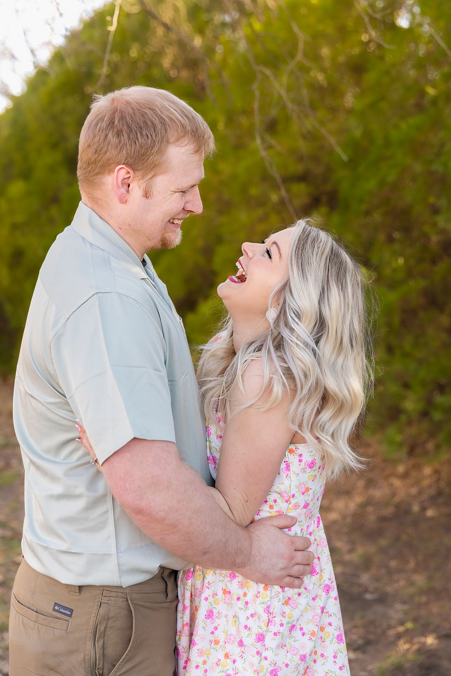 Two people sharing an intimate laughing moment together outdoors in a romantic spring photoshoot.