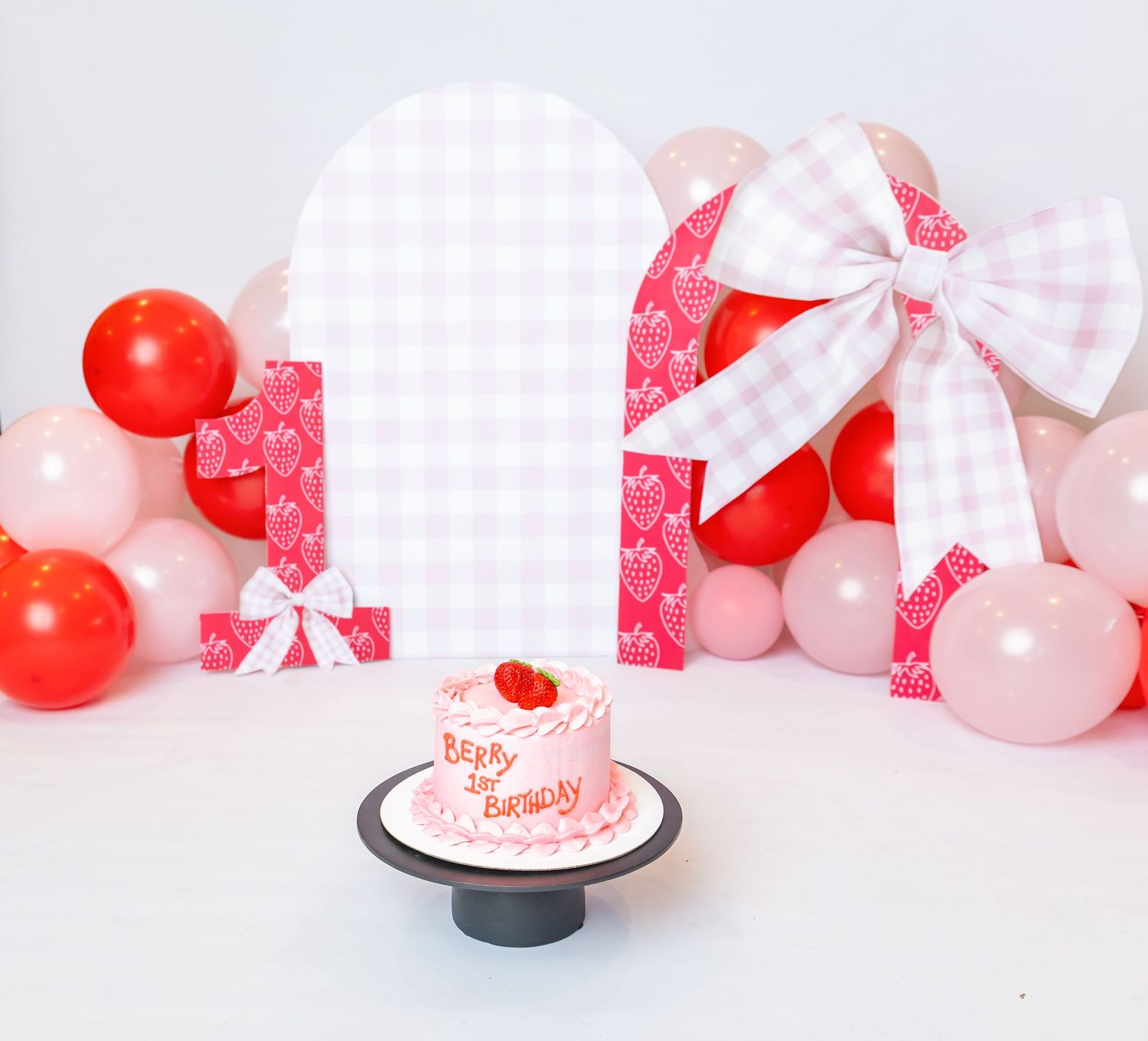Strawberry themed cake in front of 1st birthday backdrop during session with brand and family photographer, Annie Robinson Photography.