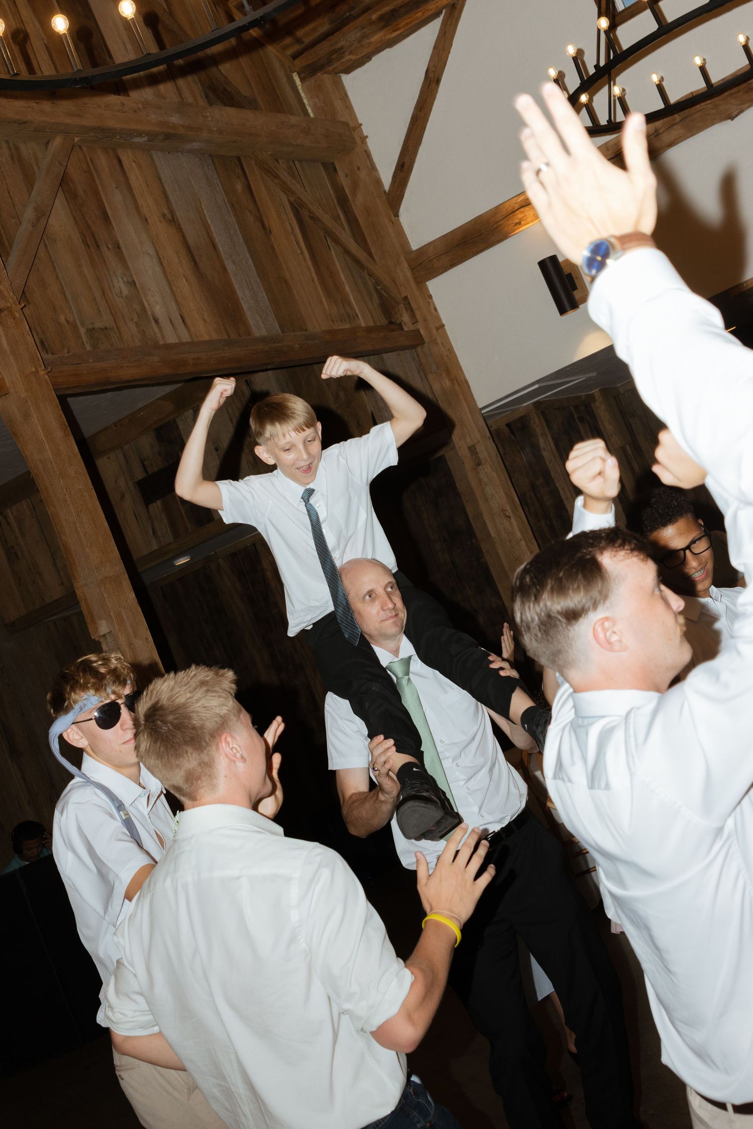 A father holds his son on his shoulders while dancing at a wedding reception in Texas.