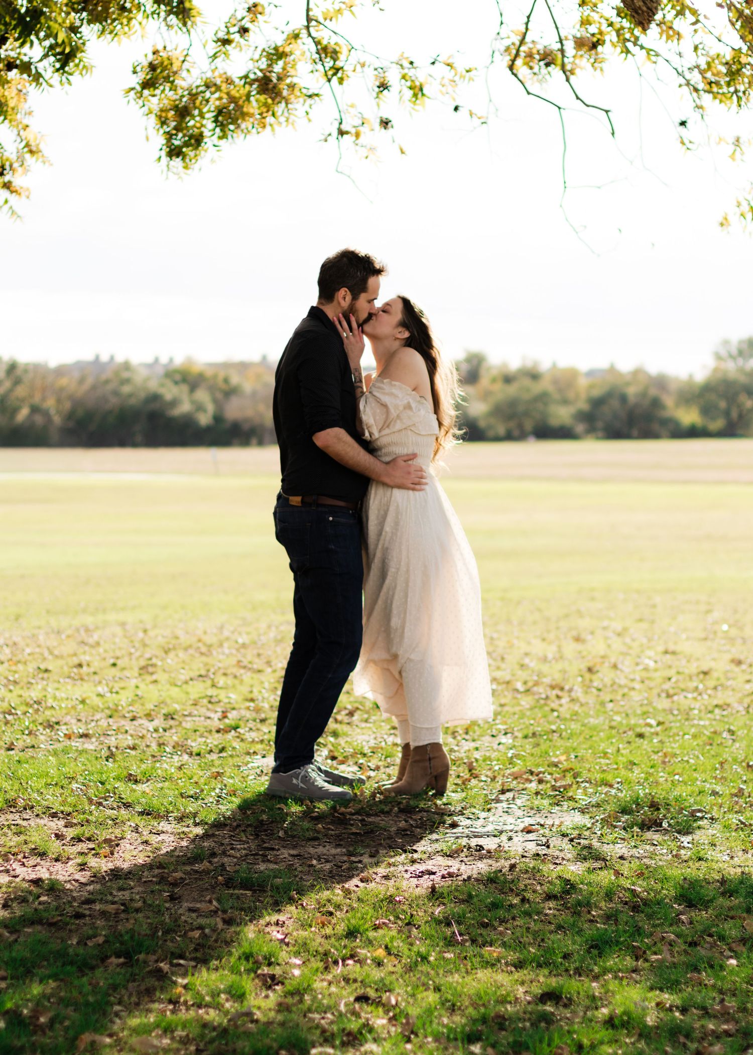 A couple kisses under an old tree at a park near Austin, Texas.