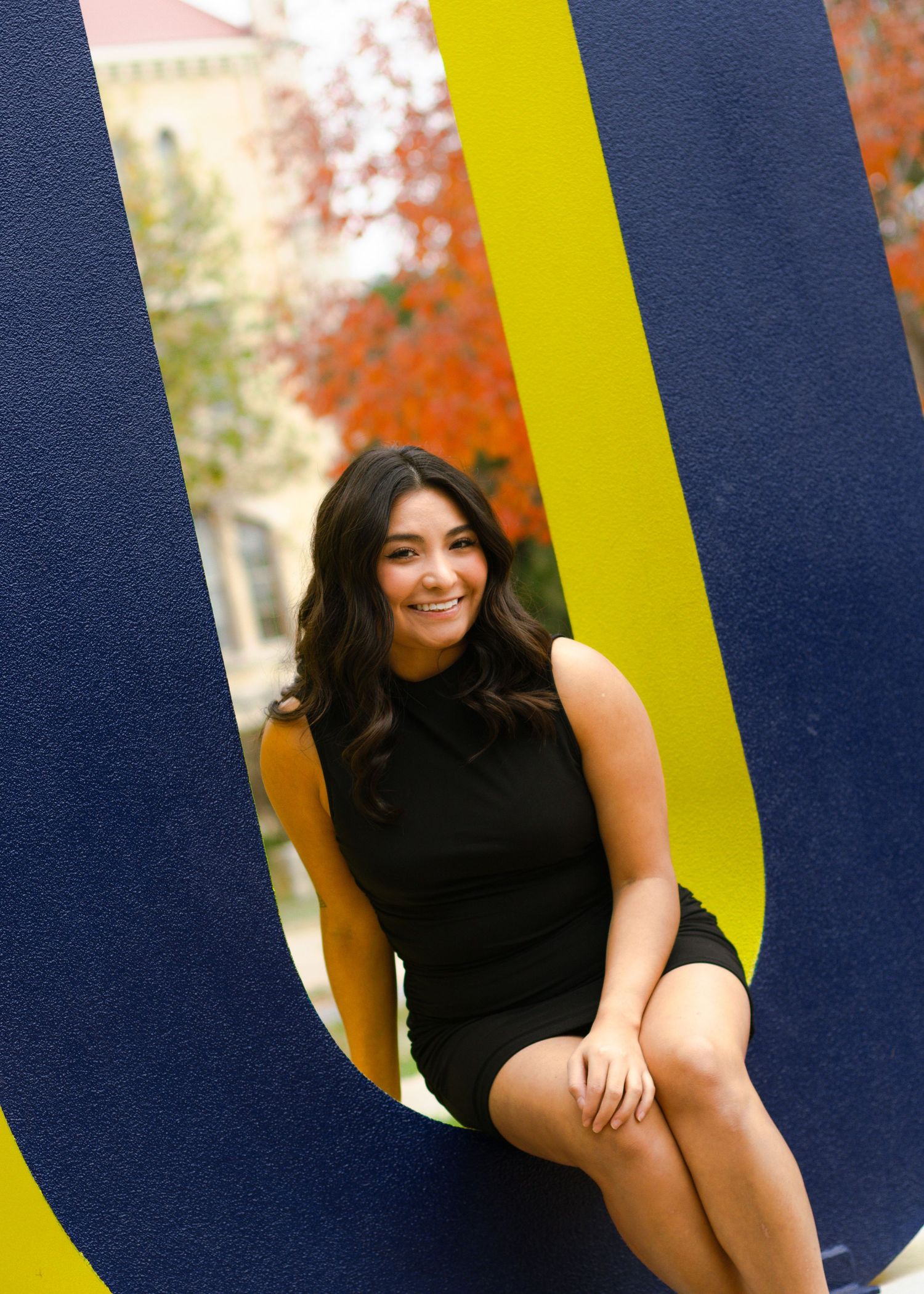 A graduating senior sits on the University letters at St. Edward's University in Austin, Texas, during her senior portraits.