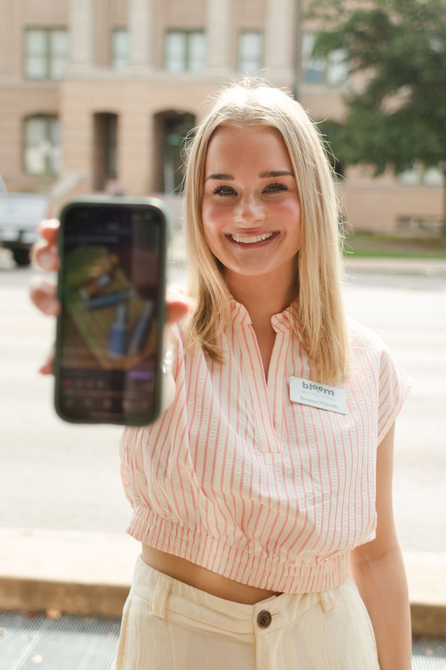 A marketing business owner poses for a branding photo while holding her phone in Georgetown, Texas.