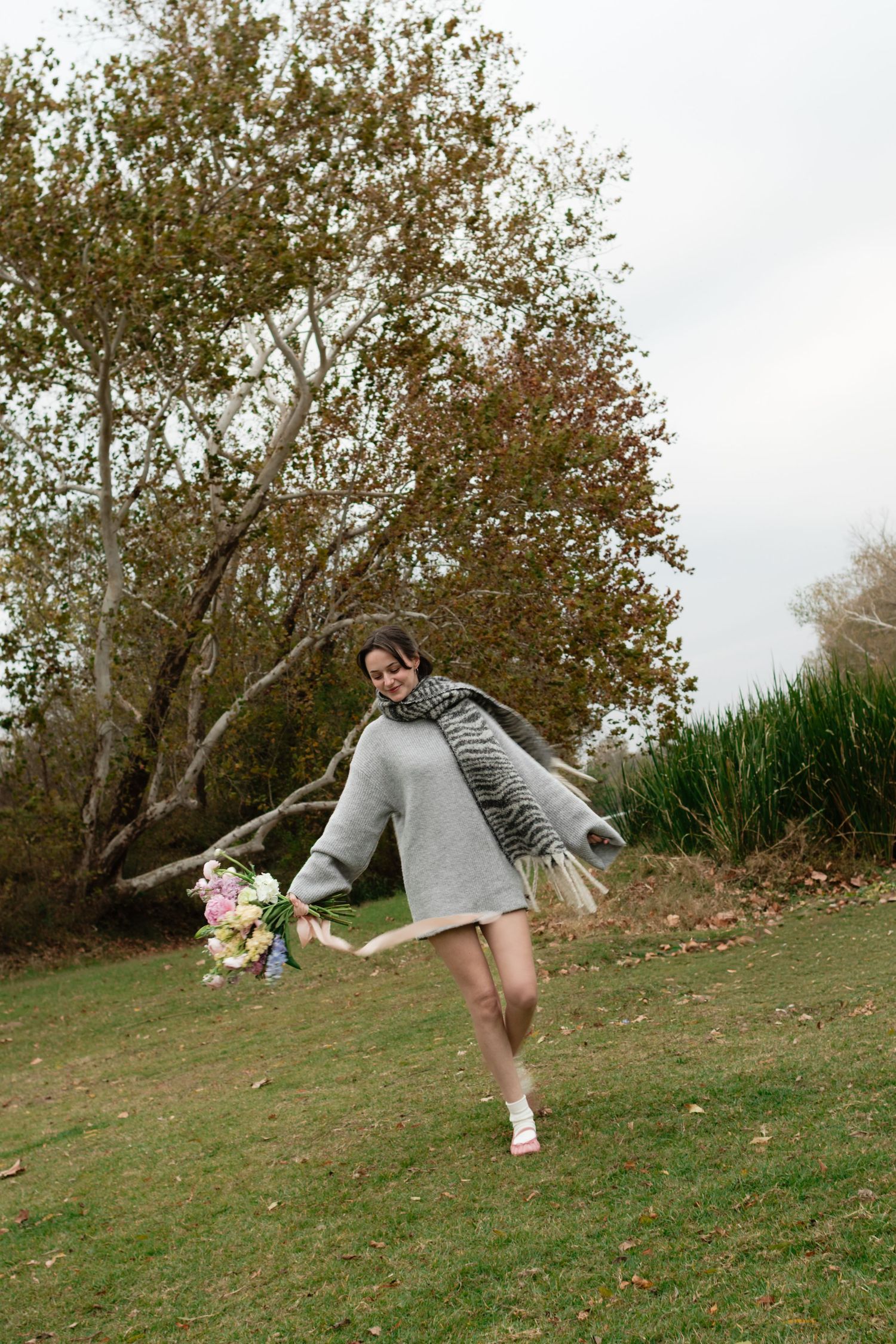 An Austin and Bastrop florist holds a bouquet while walking through a field near Bastrop, Texas, while posing for a branding photo.