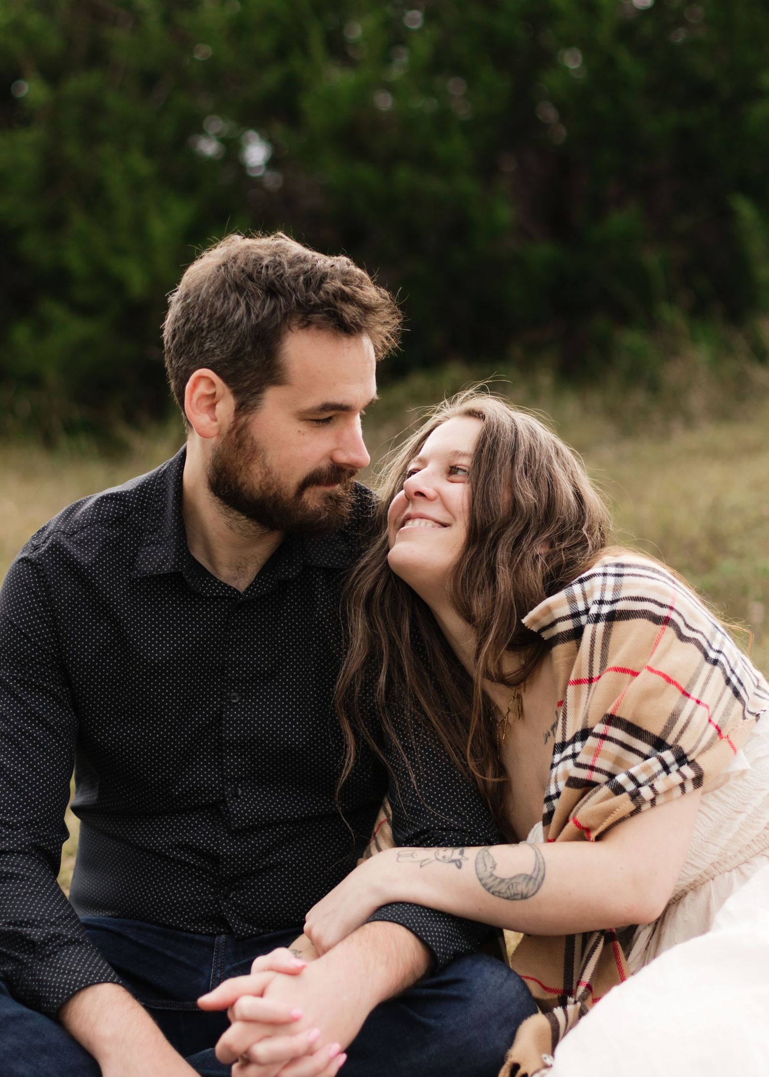 A couple sits on a blanket looking at each other at a park near Austin, Texas.