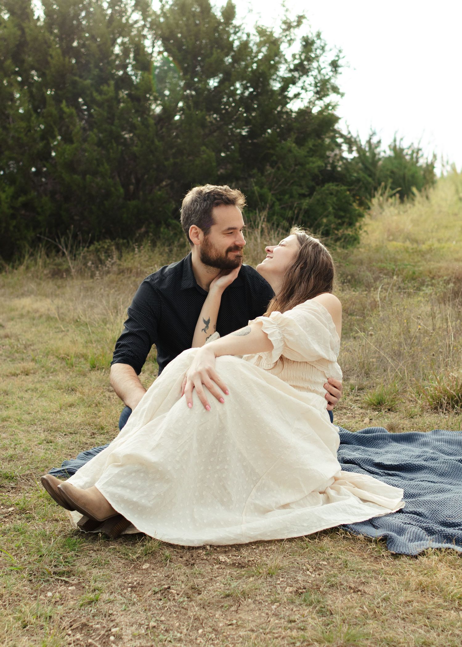A couple sits on a blanket looking at each other at a park near Austin, Texas.