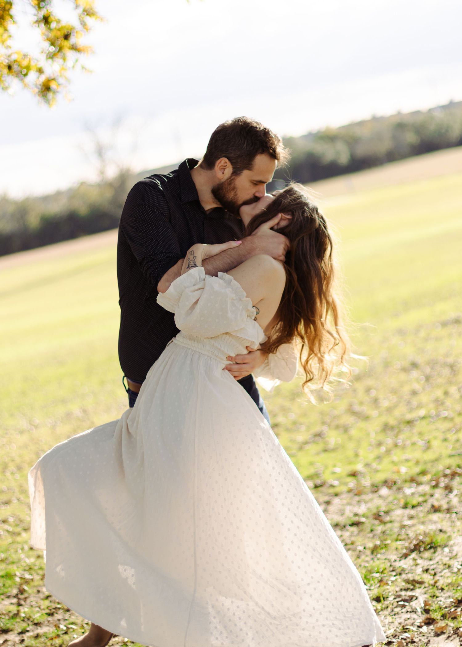 A couple kisses under an old tree at a park near Austin, Texas.
