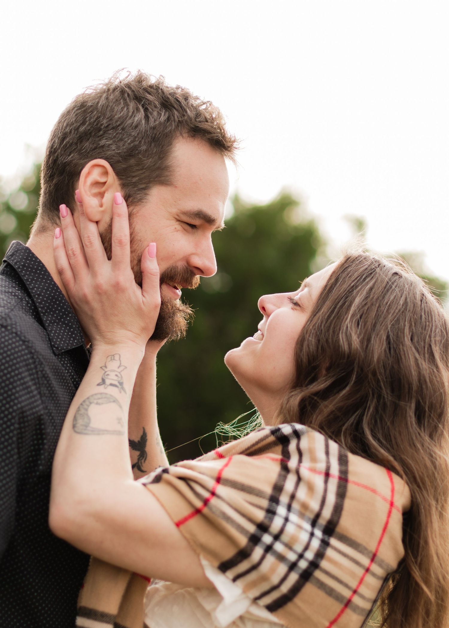 A man looks at the camera while a woman holds his face at a park near Austin, Texas.