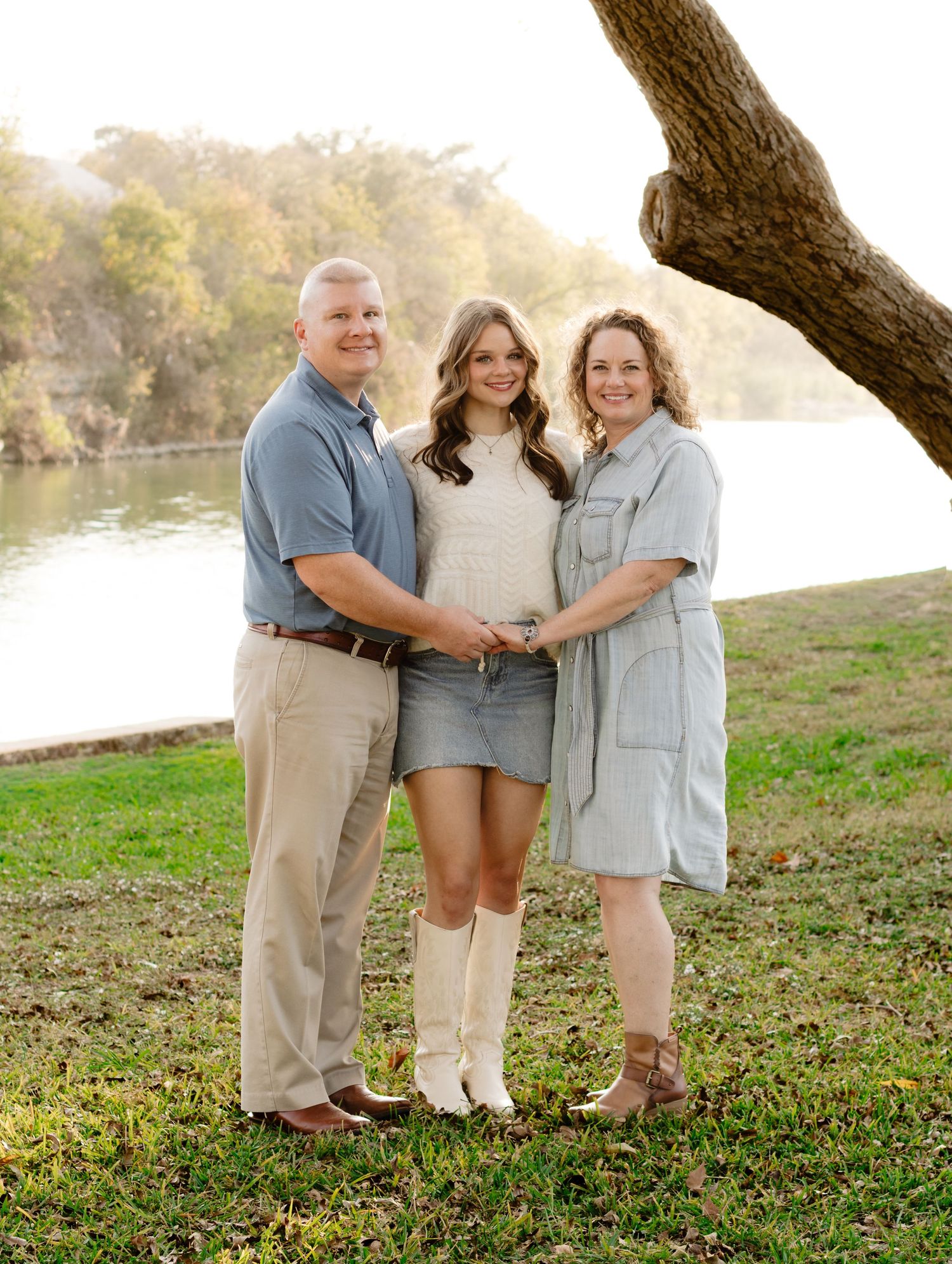 A daughter and her parents smile during a photo shoot at San Gabriel Park in Georgetown, Texas.