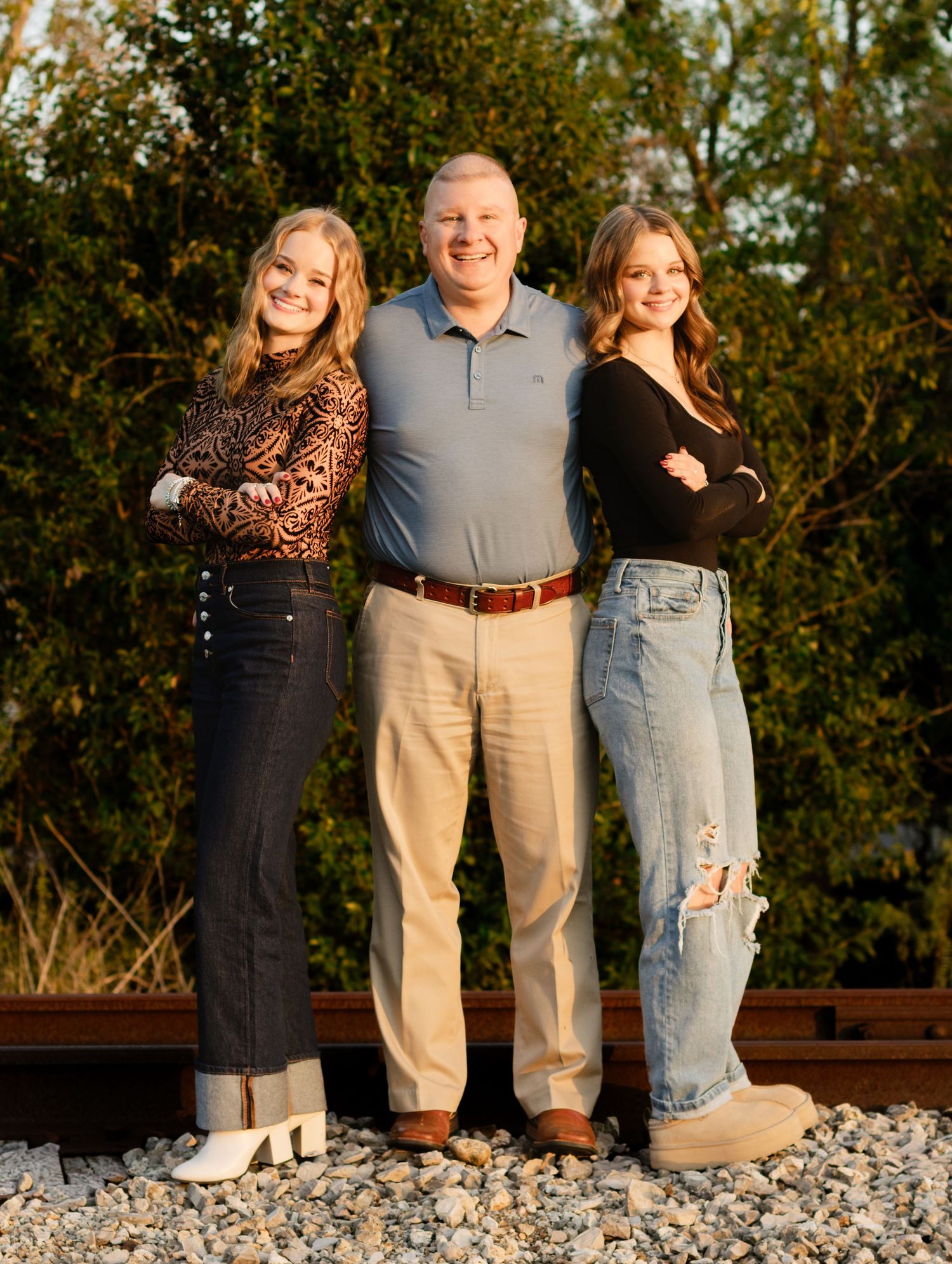 A dad and his daughters pose on an abandoned railroad track during a photo shoot in Georgetown, Texas.