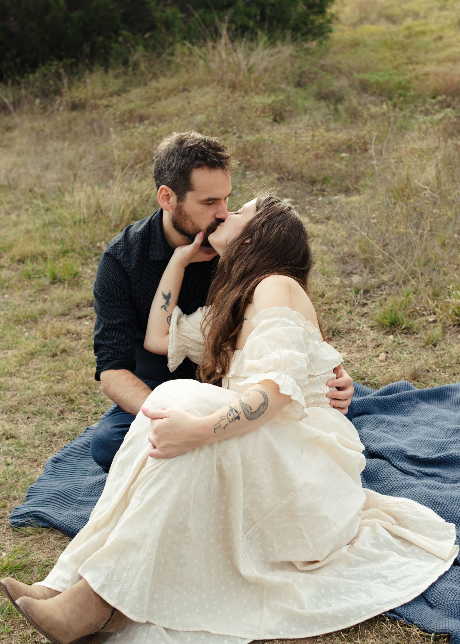 A couple sits on a blanket and kisses near Austin, Texas.