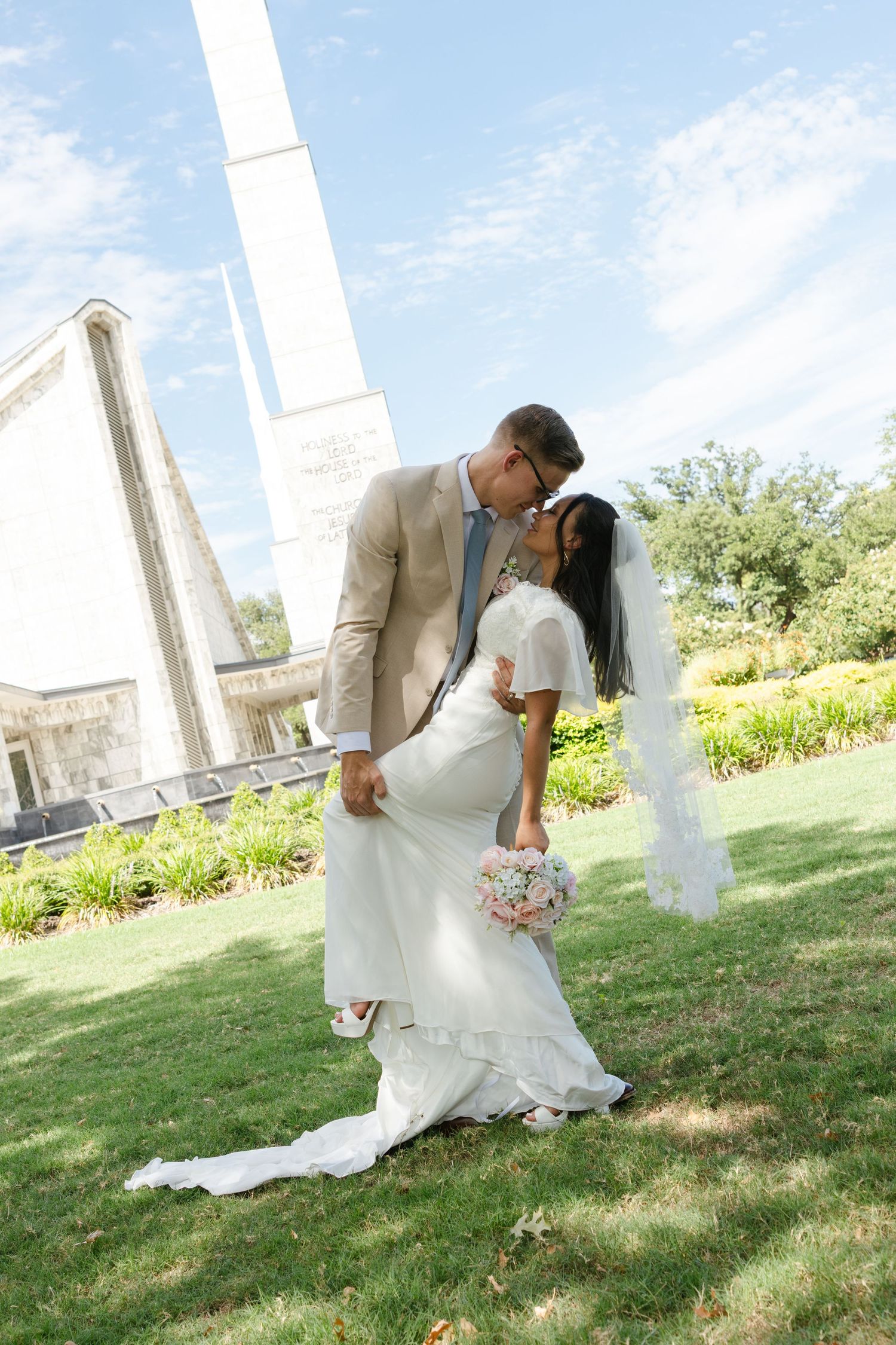 A groom dips his bride into a kiss in front of the Latter Day Saints temple in Dallas, Texas.