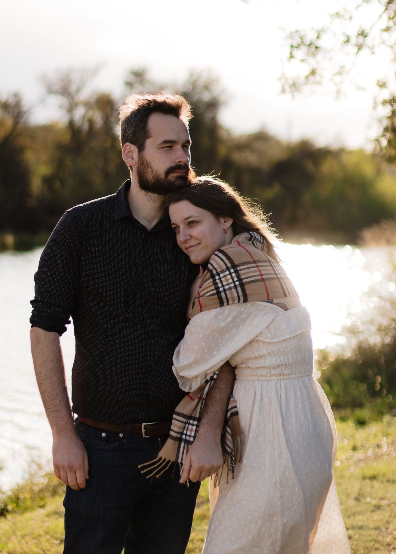 A couple looks into the distance while holding each other near a lake in Austin, Texas.
