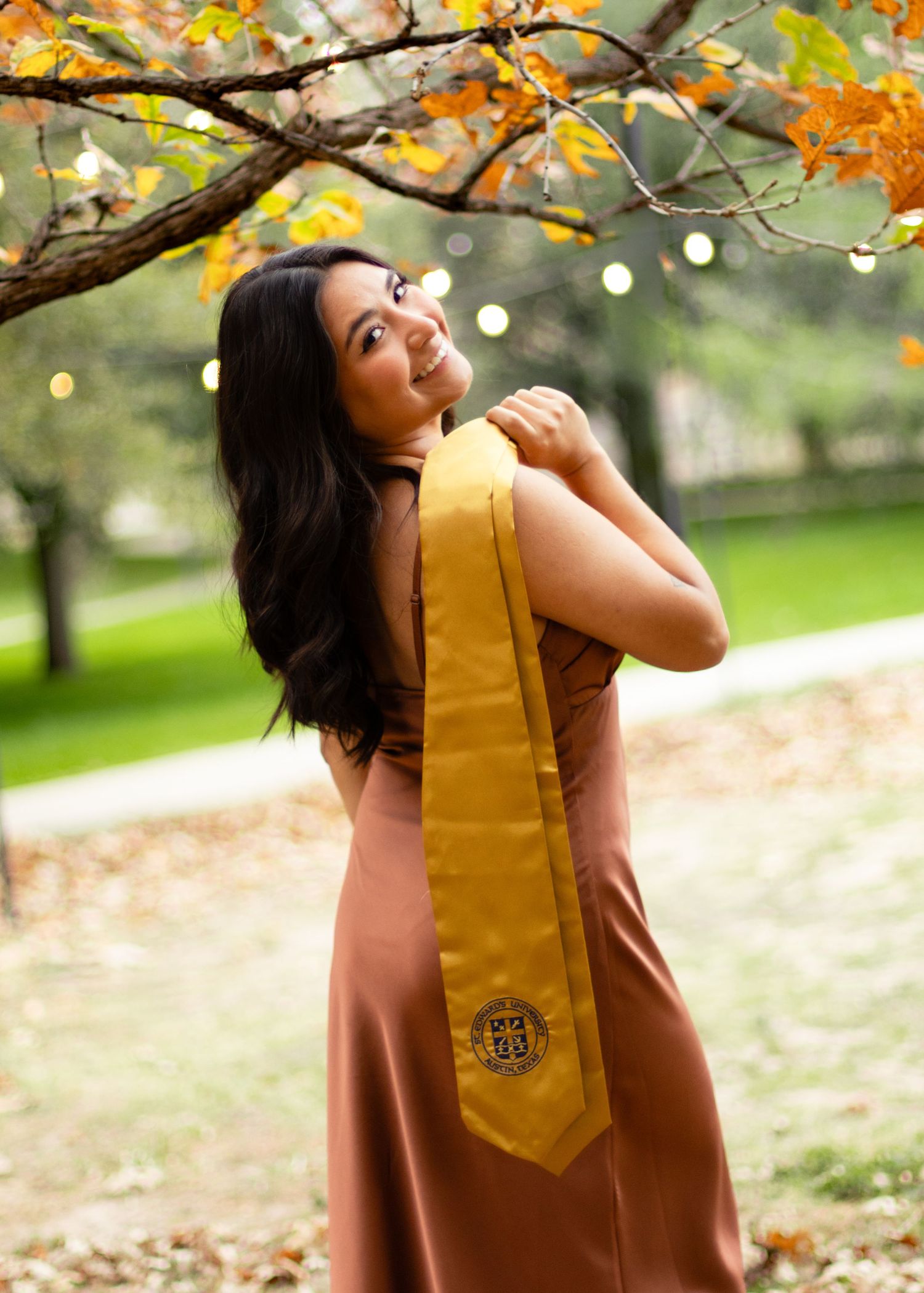 A graduating college senior holds her regalia at St. Edward's University in Austin, Texas, during her senior portraits.