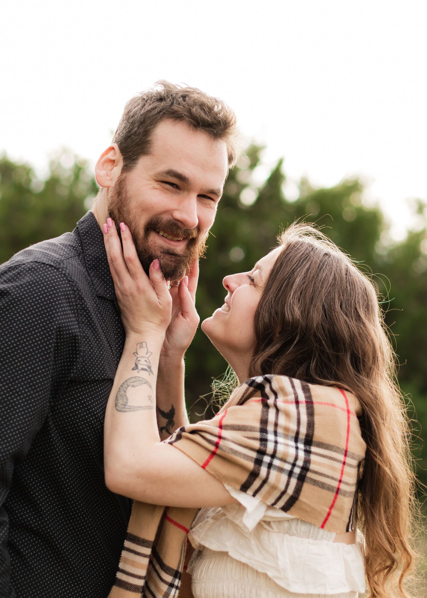 A man looks at the camera while a woman holds his face at a park near Austin, Texas.