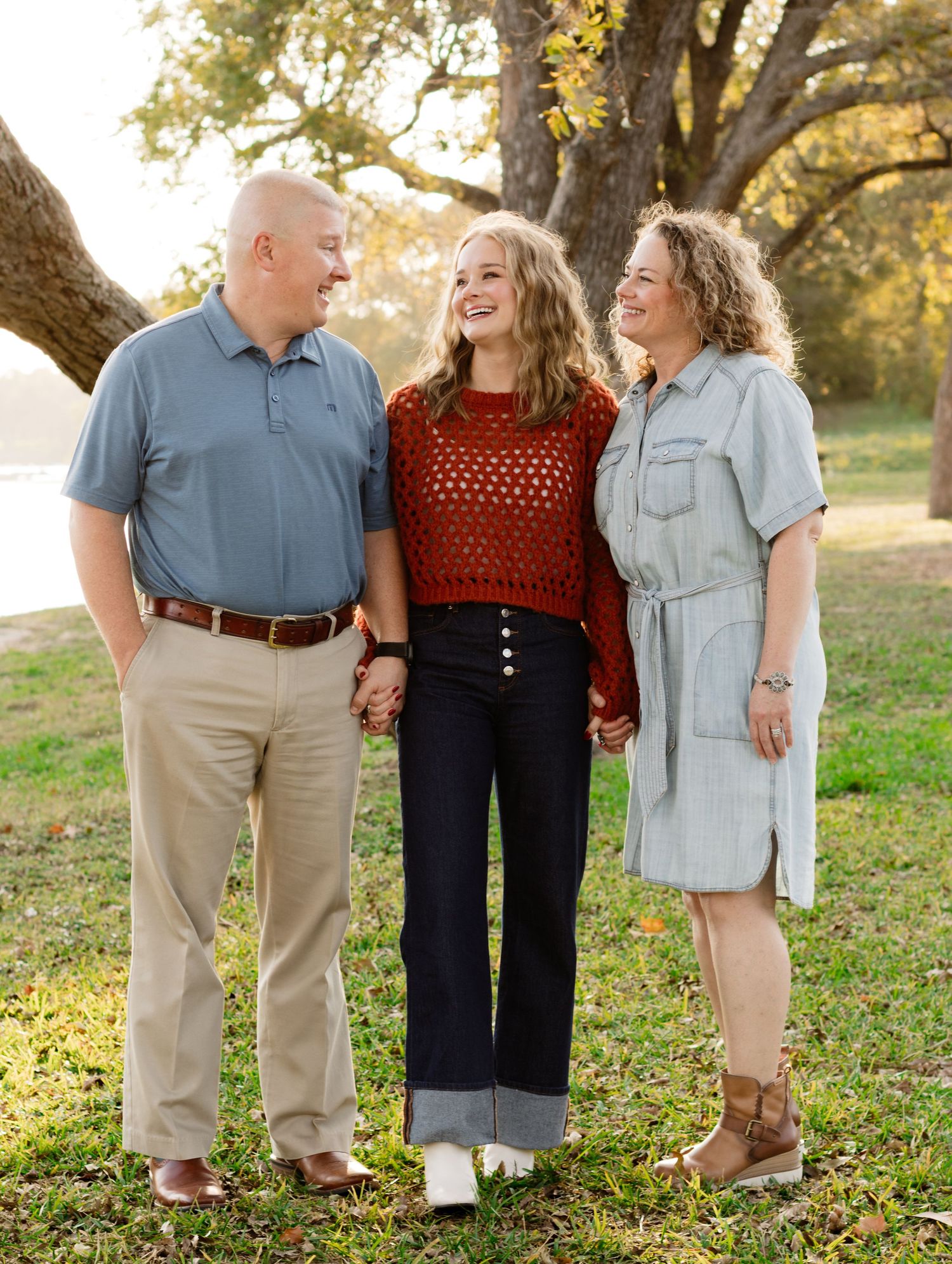 A daughter and her parents smile and laugh during a photo shoot at San Gabriel Park in Georgetown, Texas.