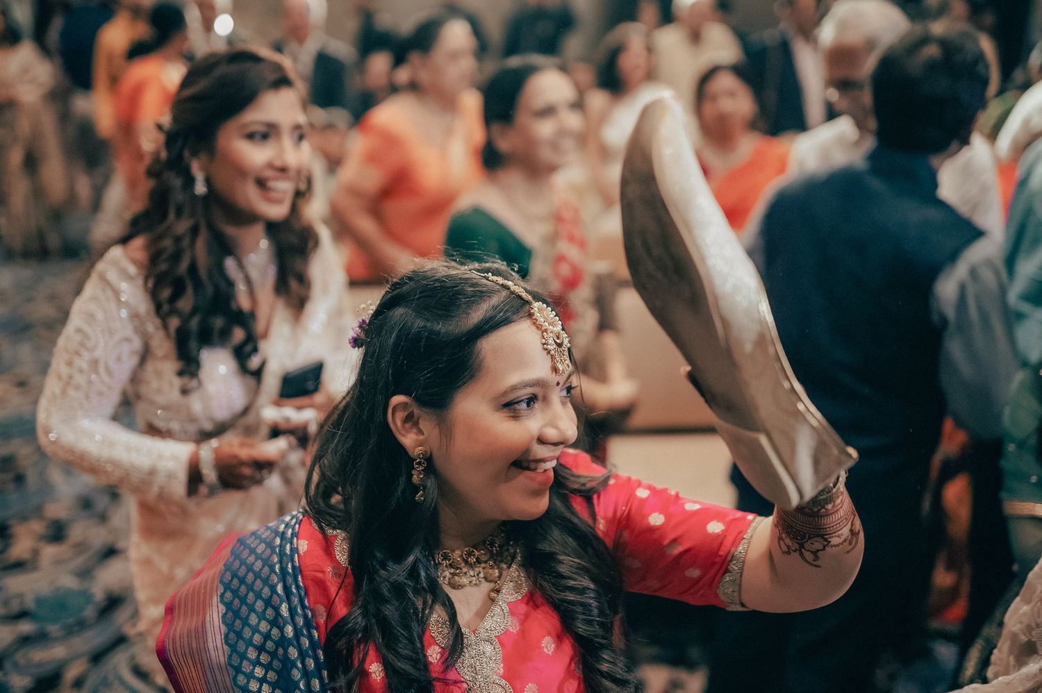 Indian bride in red lehenga holds decorative plate during vibrant traditional wedding celebration ceremony.