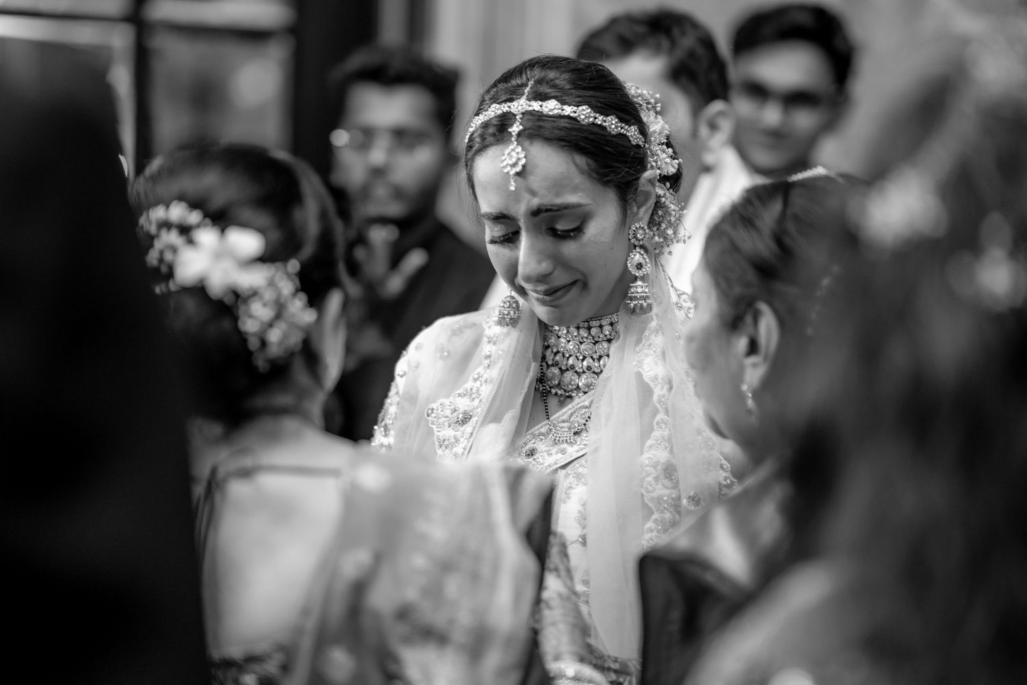 Tearful Indian bride in traditional bridal jewelry and veil at her wedding ceremony.
