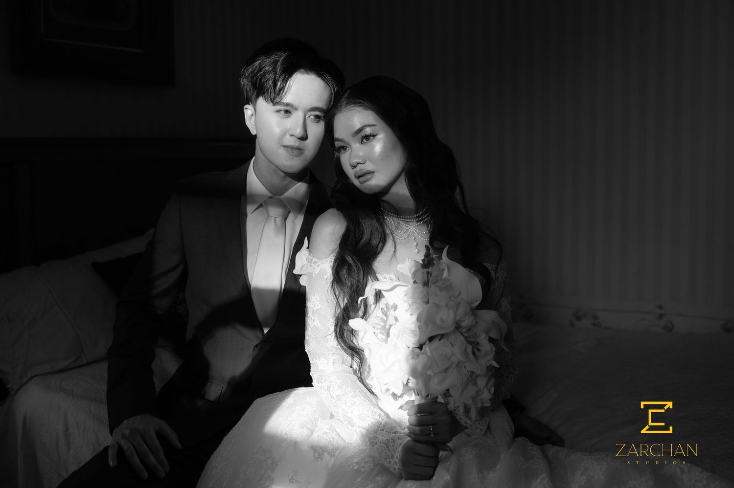 Black and white portrait of bride and groom sitting together intimately on wedding day.