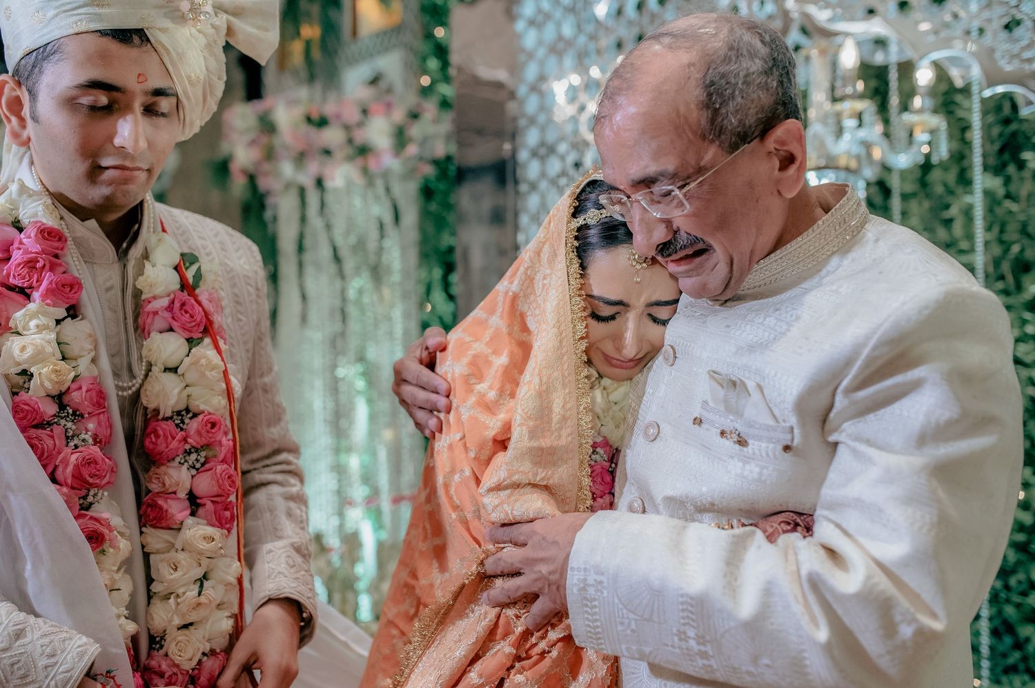 Father escorts bride in peach lehenga during emotional traditional Indian wedding ceremony.
