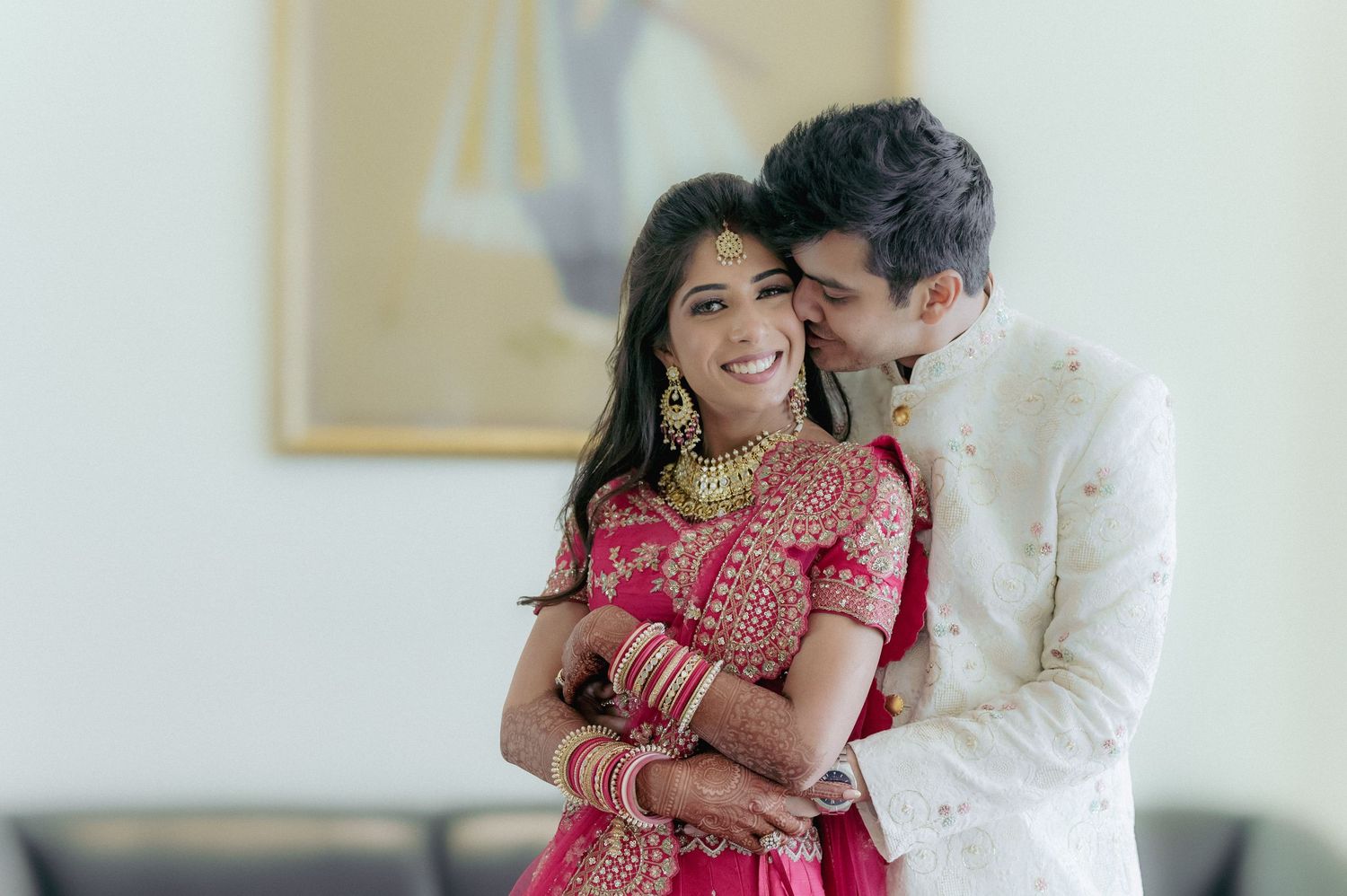 Indian bride and groom in traditional wedding attire share a joyful romantic embrace.