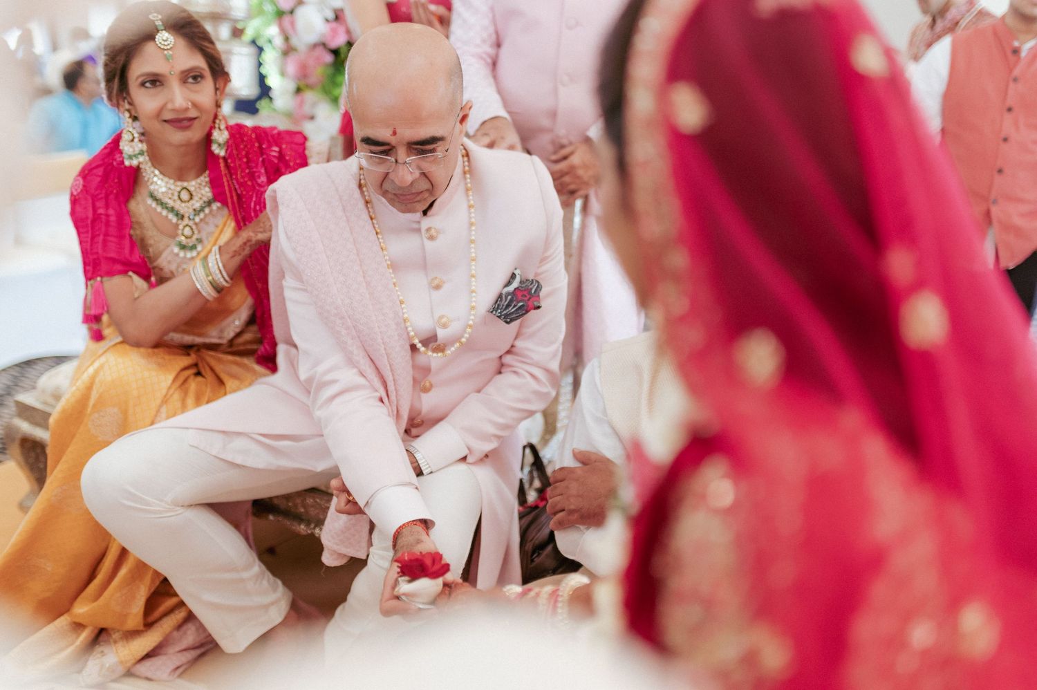 Family elder performing traditional foot washing ritual during Indian Hindu wedding ceremony.