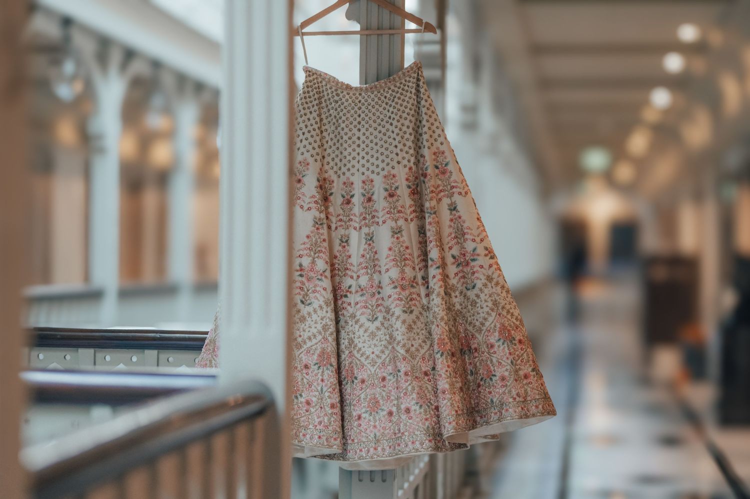Ornate embroidered Indian lehenga skirt hanging on display in an elegant corridor.