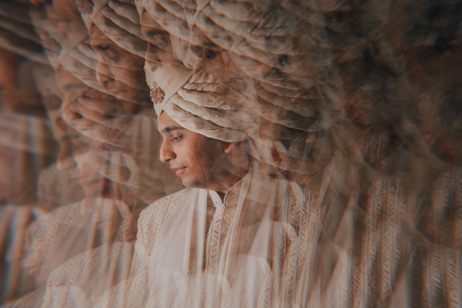 A dreamy double-exposure portrait of an Indian groom in a white turban and sherwani.