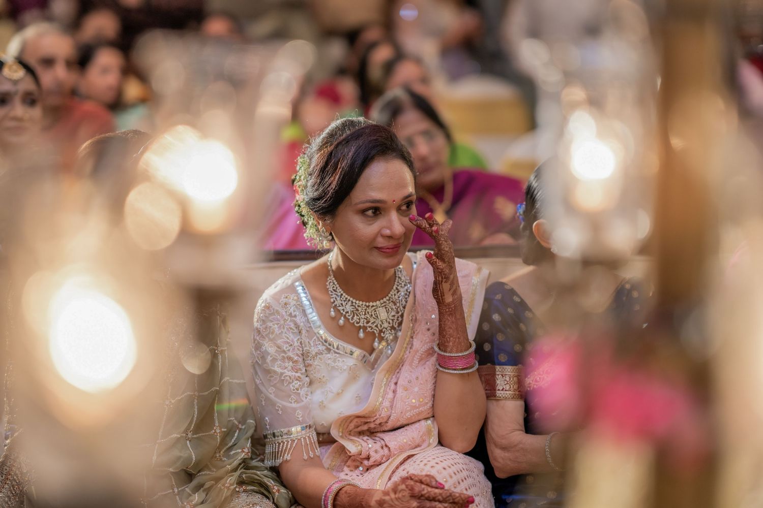Emotional Indian wedding guest in white saree with jewelry watches ceremony with tears.