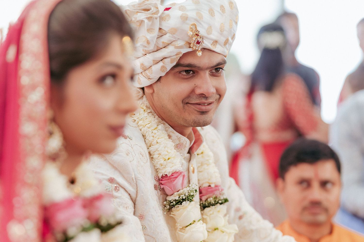 Indian groom in embroidered sherwani smiling during traditional Hindu wedding ceremony.