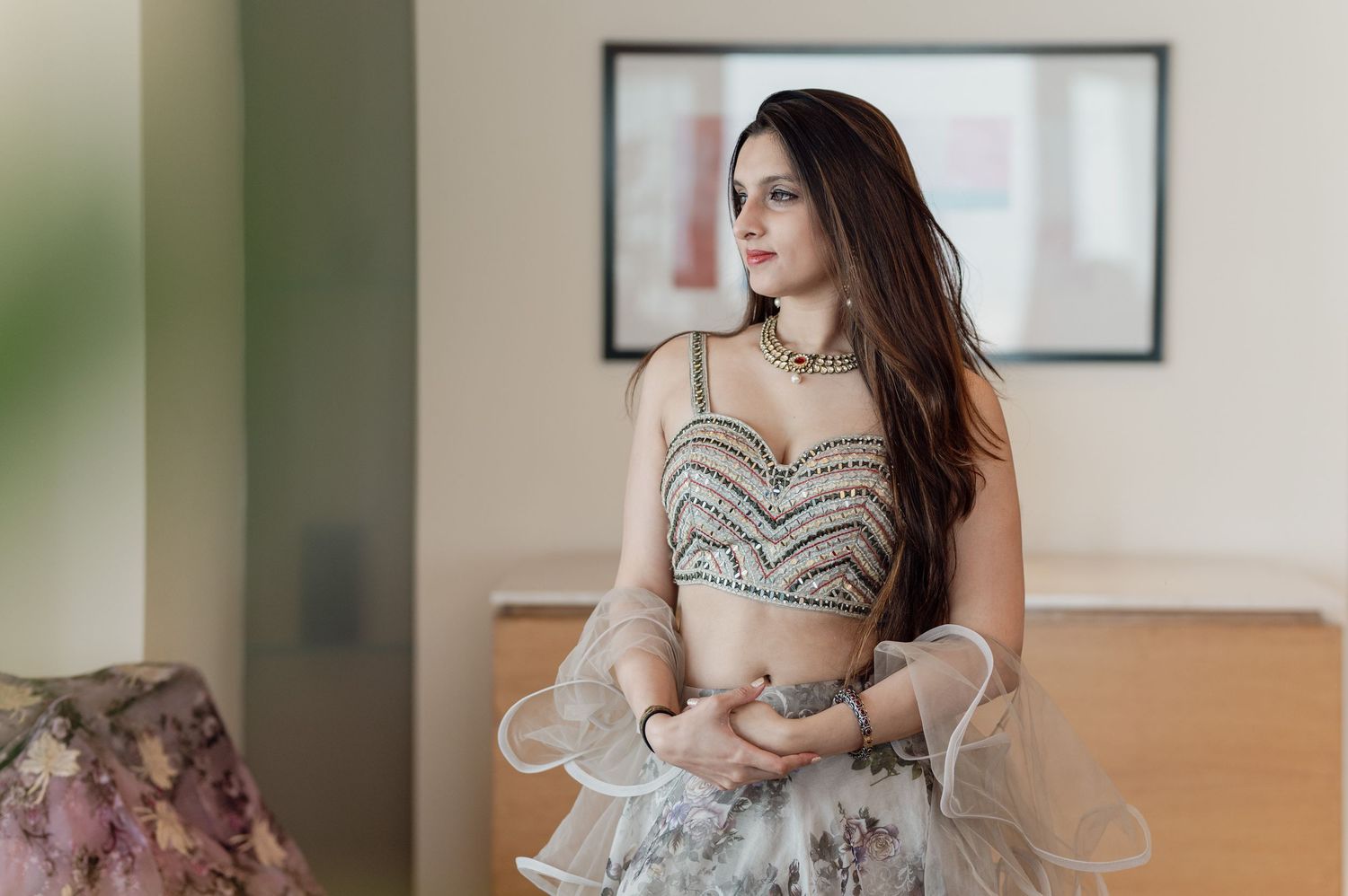 Bride in embroidered lehenga choli with choker necklace looking away.