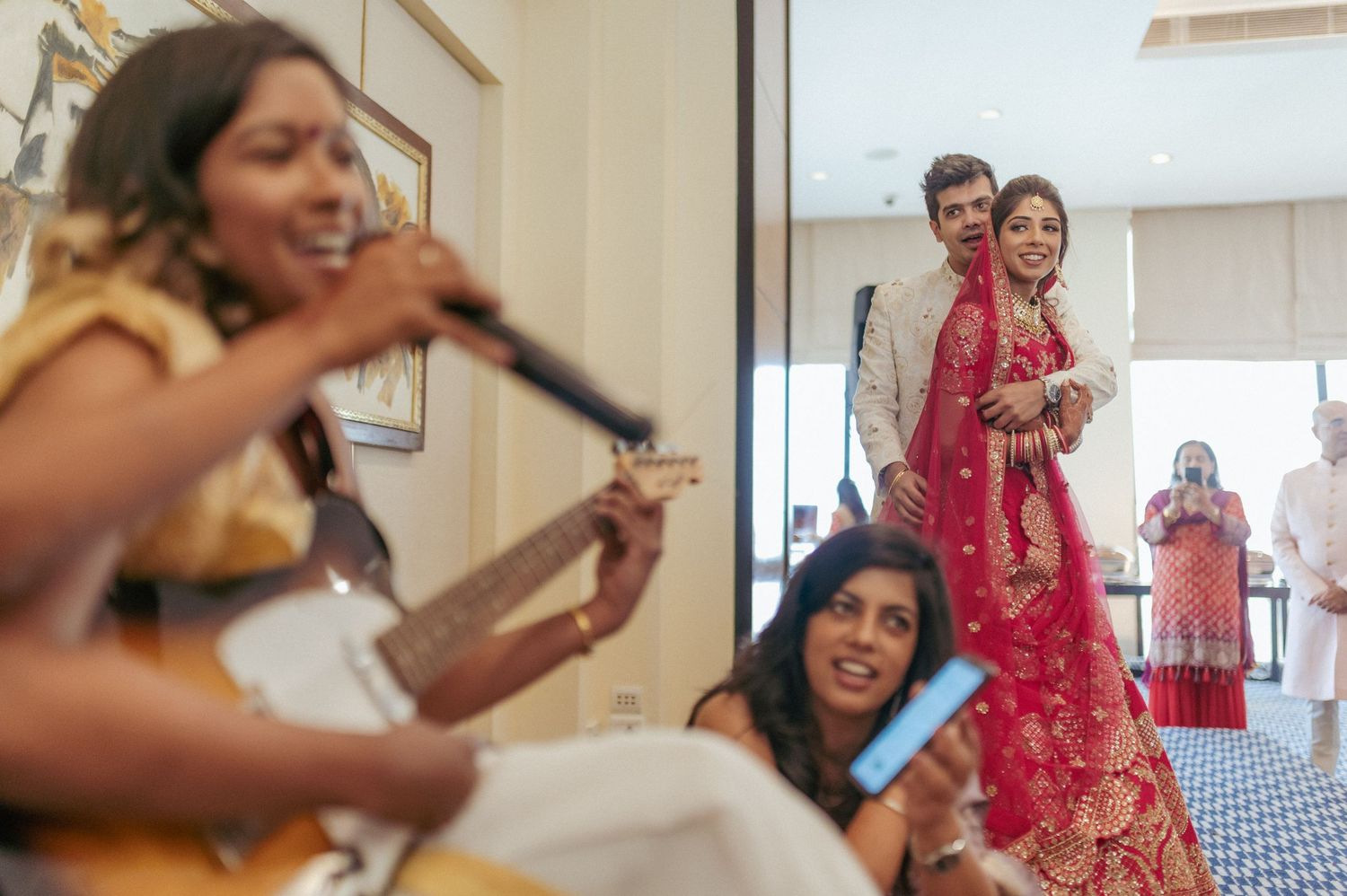 Live musician playing guitar for Indian bride and groom in traditional wedding attire.