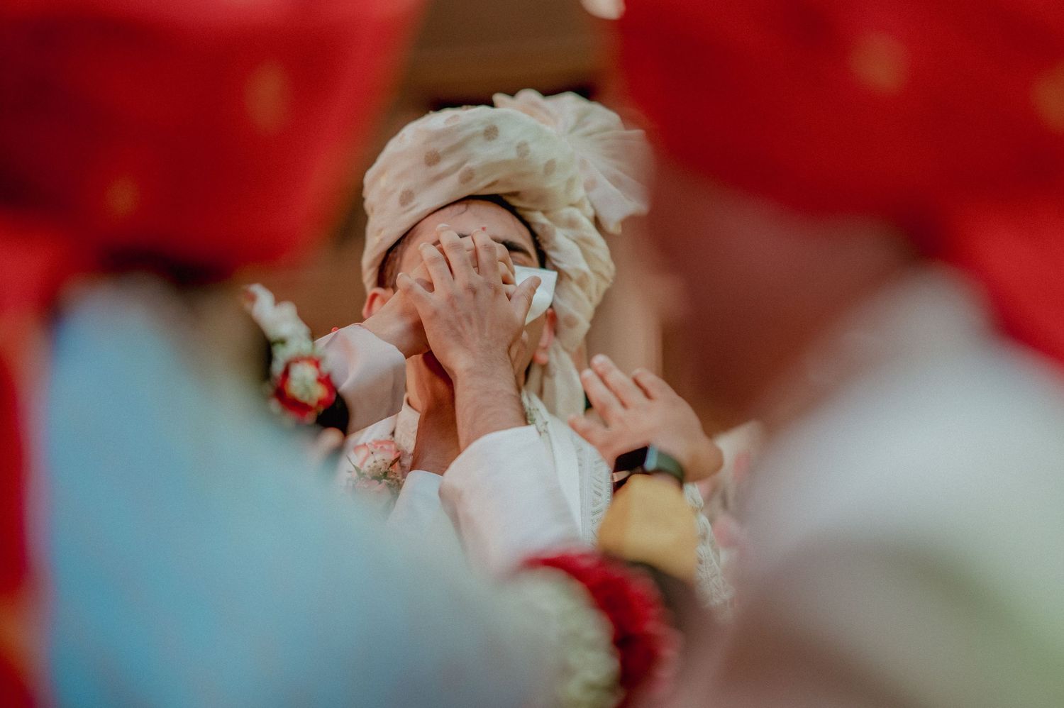 Emotional Indian groom covering face with hands during touching wedding ceremony moment.