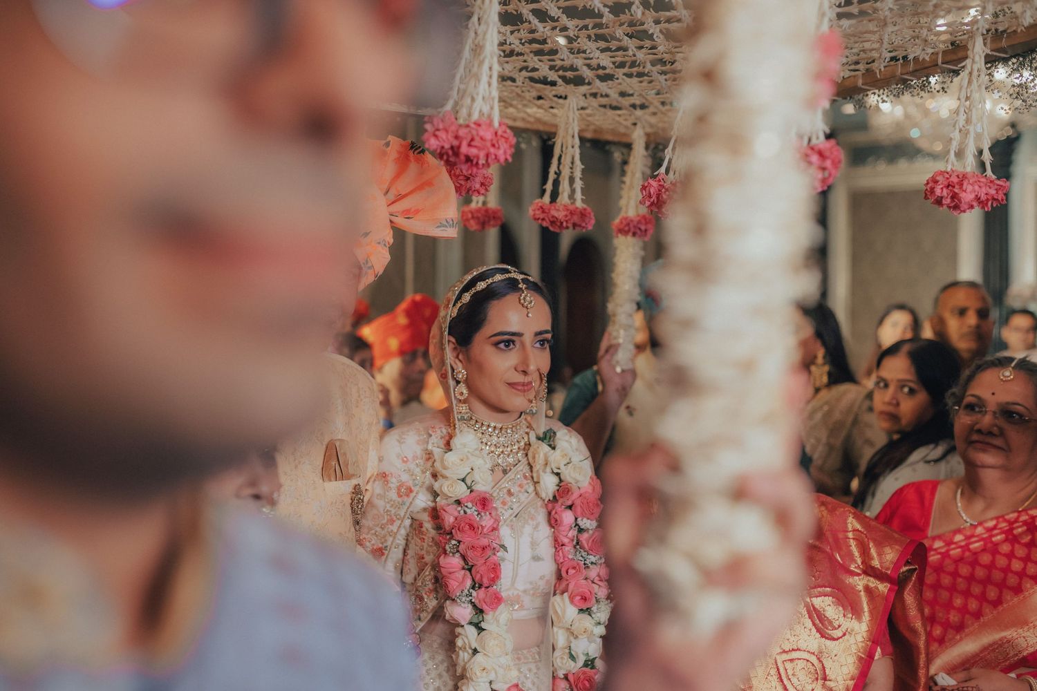 Indian bride adorned with floral garland making her grand entrance at traditional wedding ceremony.