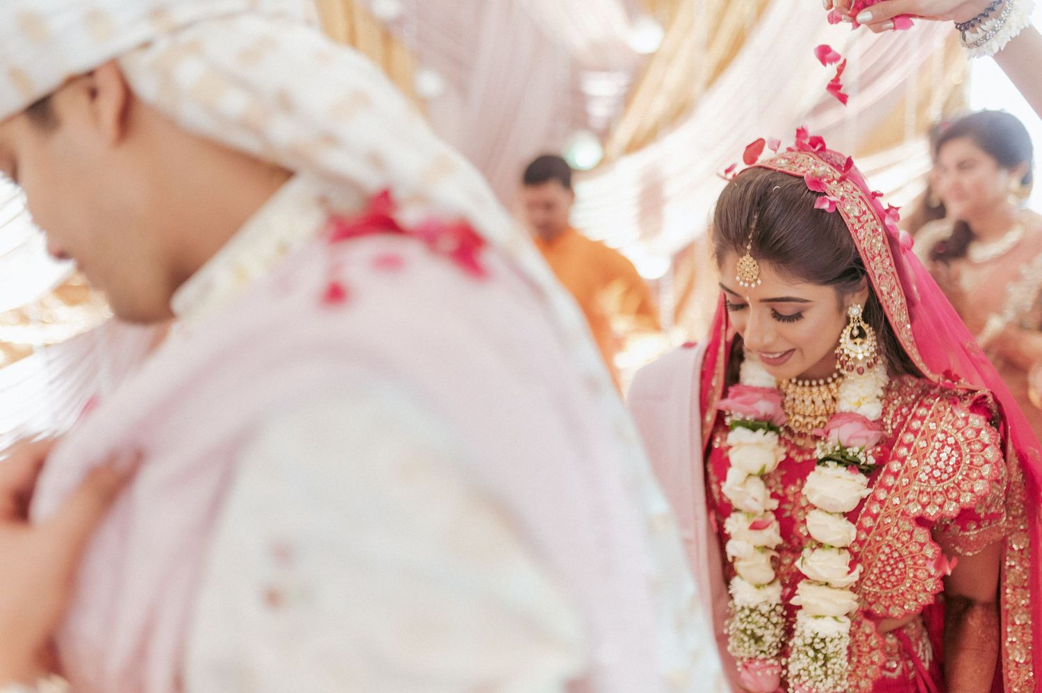 Indian bride in red lehenga bowing during traditional Hindu wedding ceremony ritual.