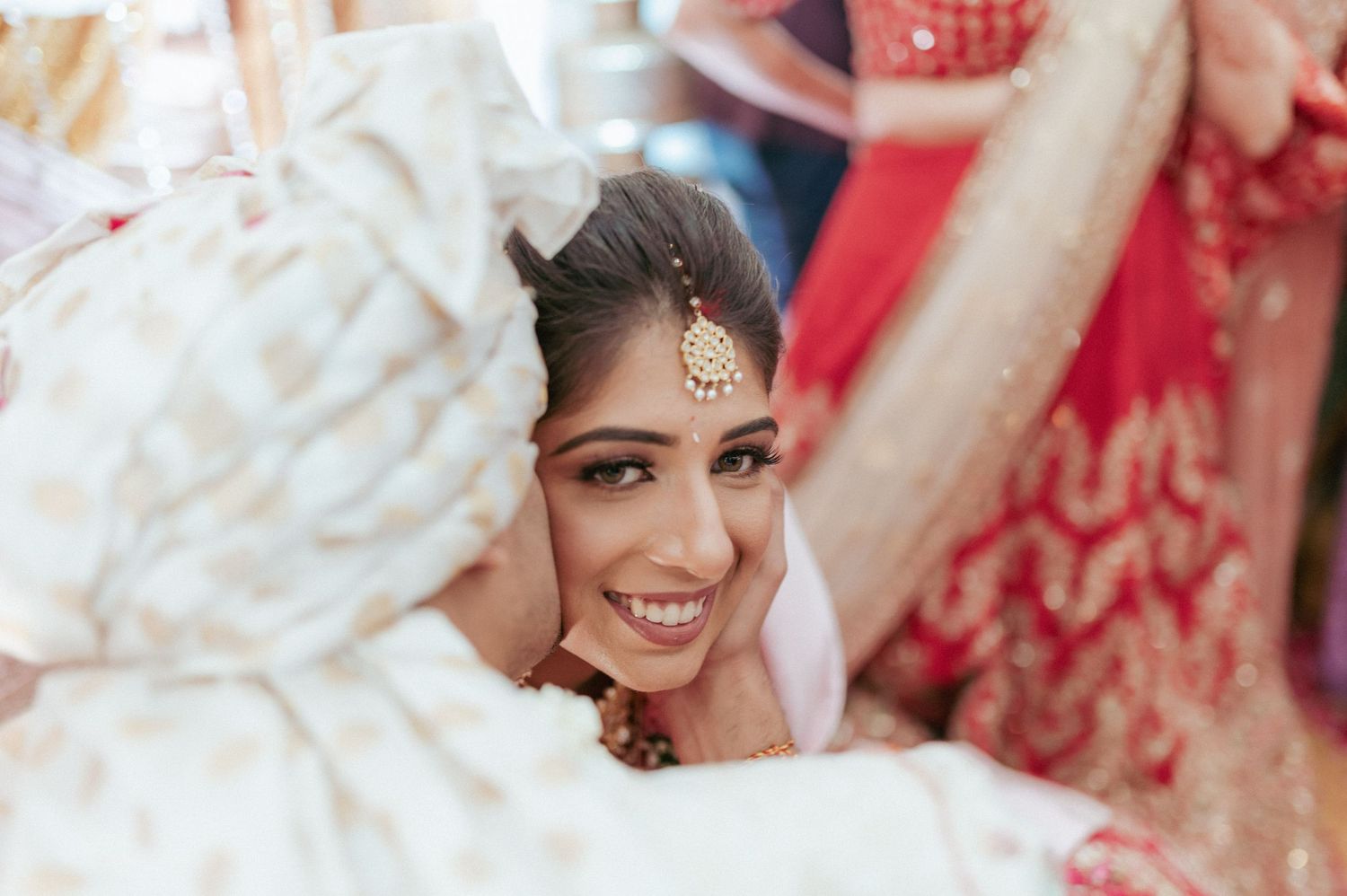 Beautiful Indian bride in red bridal attire smiles joyfully during her traditional Hindu wedding ceremony.