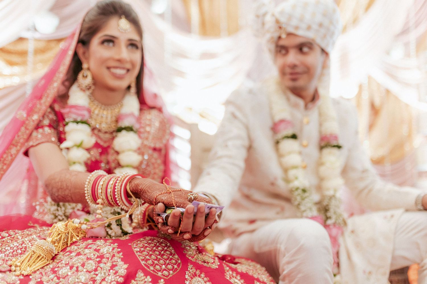 Indian bride and groom in traditional attire holding hands during Hindu wedding ceremony.
