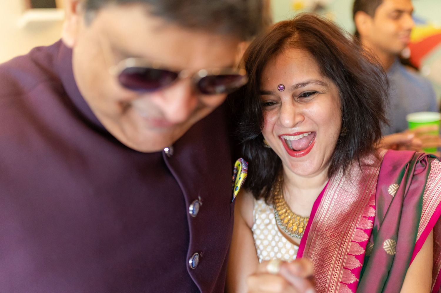 Couple sharing a joyful laughing moment together at a colorful Indian celebration.
