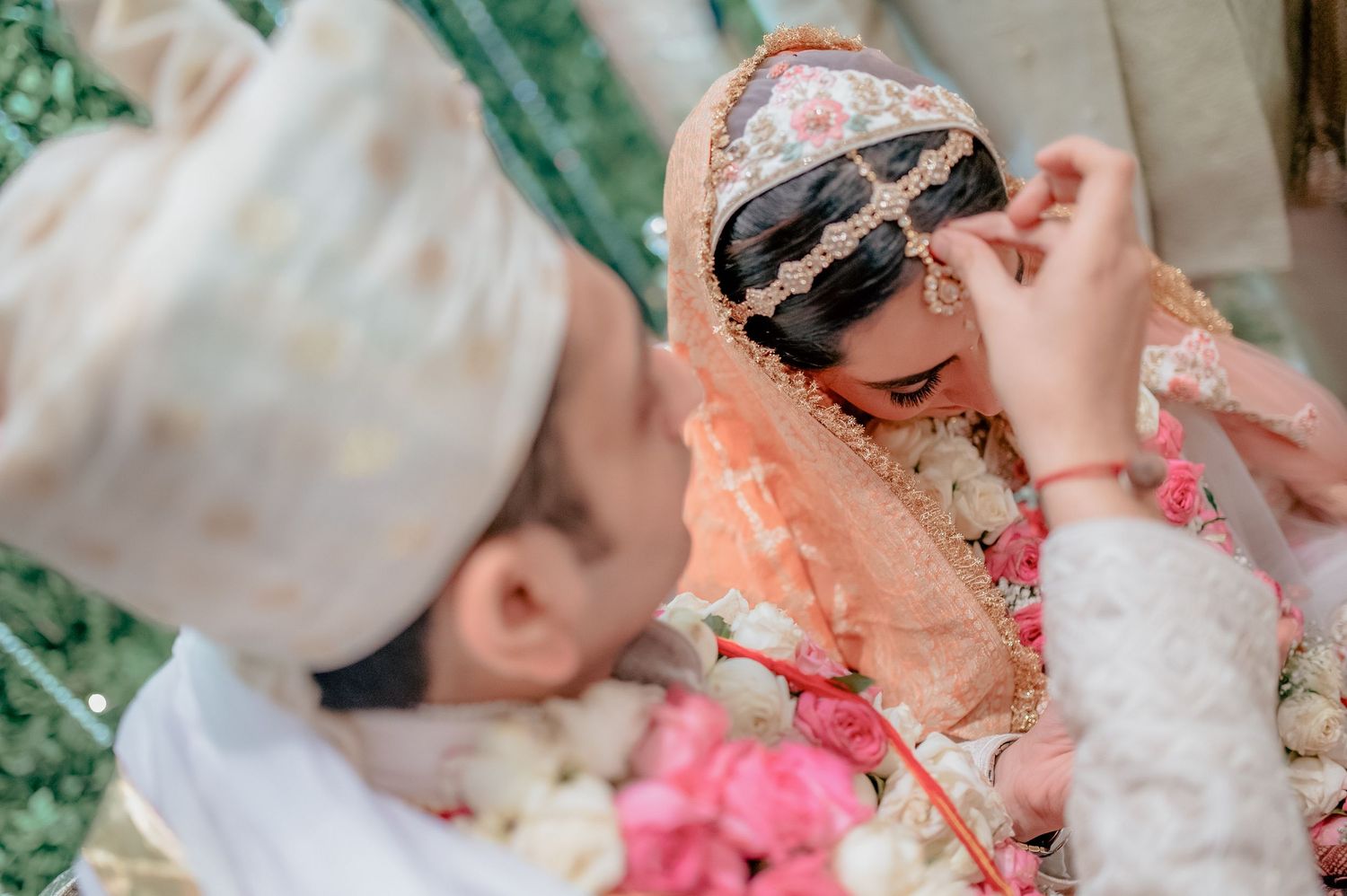 Groom adjusts brides golden dupatta during elegant traditional Indian wedding ceremony.