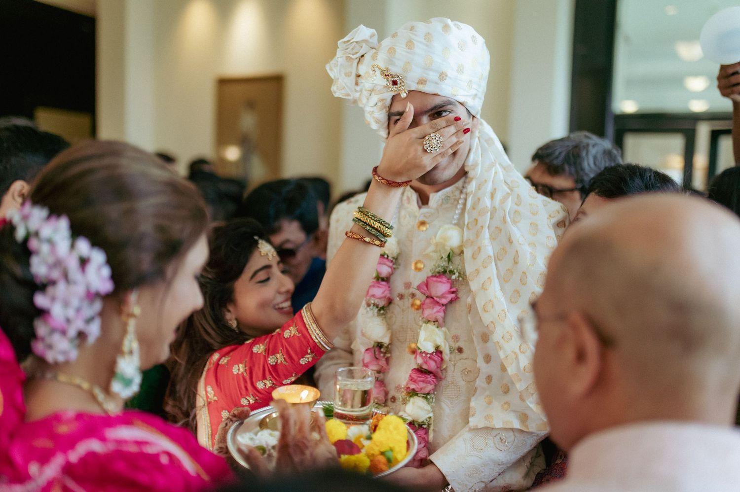 Indian groom in floral garland participates in traditional wedding ritual ceremony.