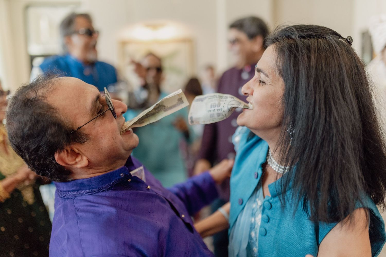 Couple shares a champagne bottle drink together at a lively Indian wedding reception party.