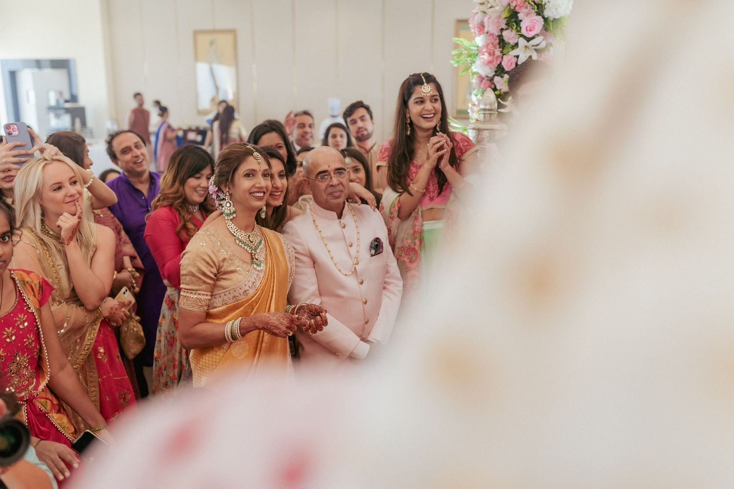 Joyful wedding guests in colorful traditional Indian attire smile and celebrate during wedding ceremony.