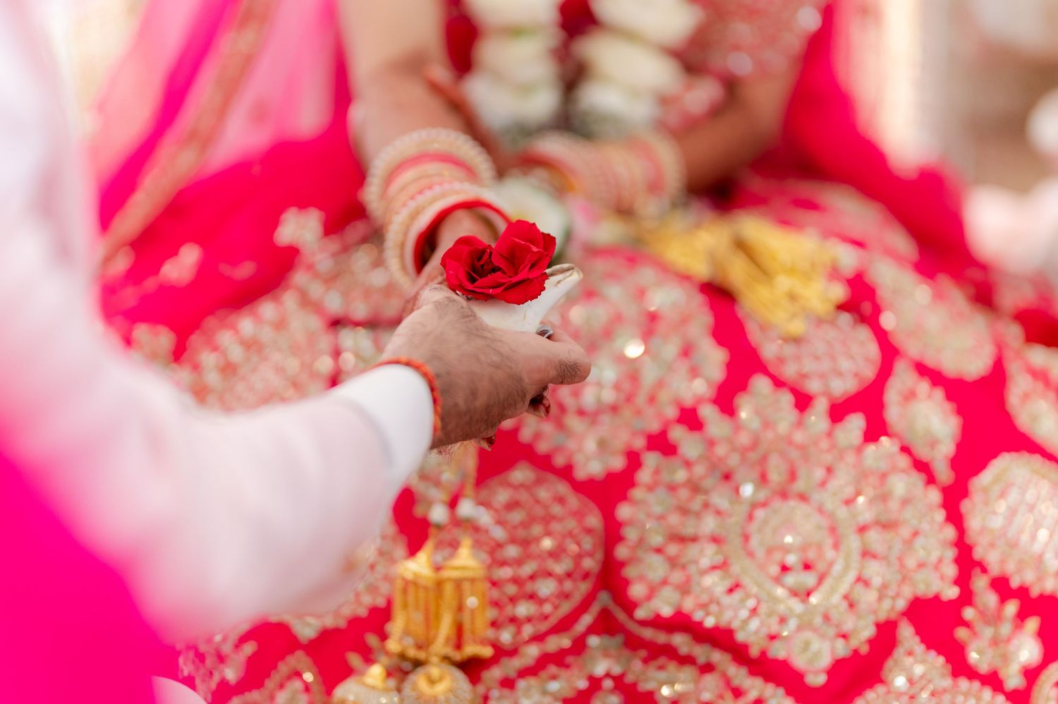 Close-up of red roses in bowl during traditional Hindu wedding ceremony ritual.